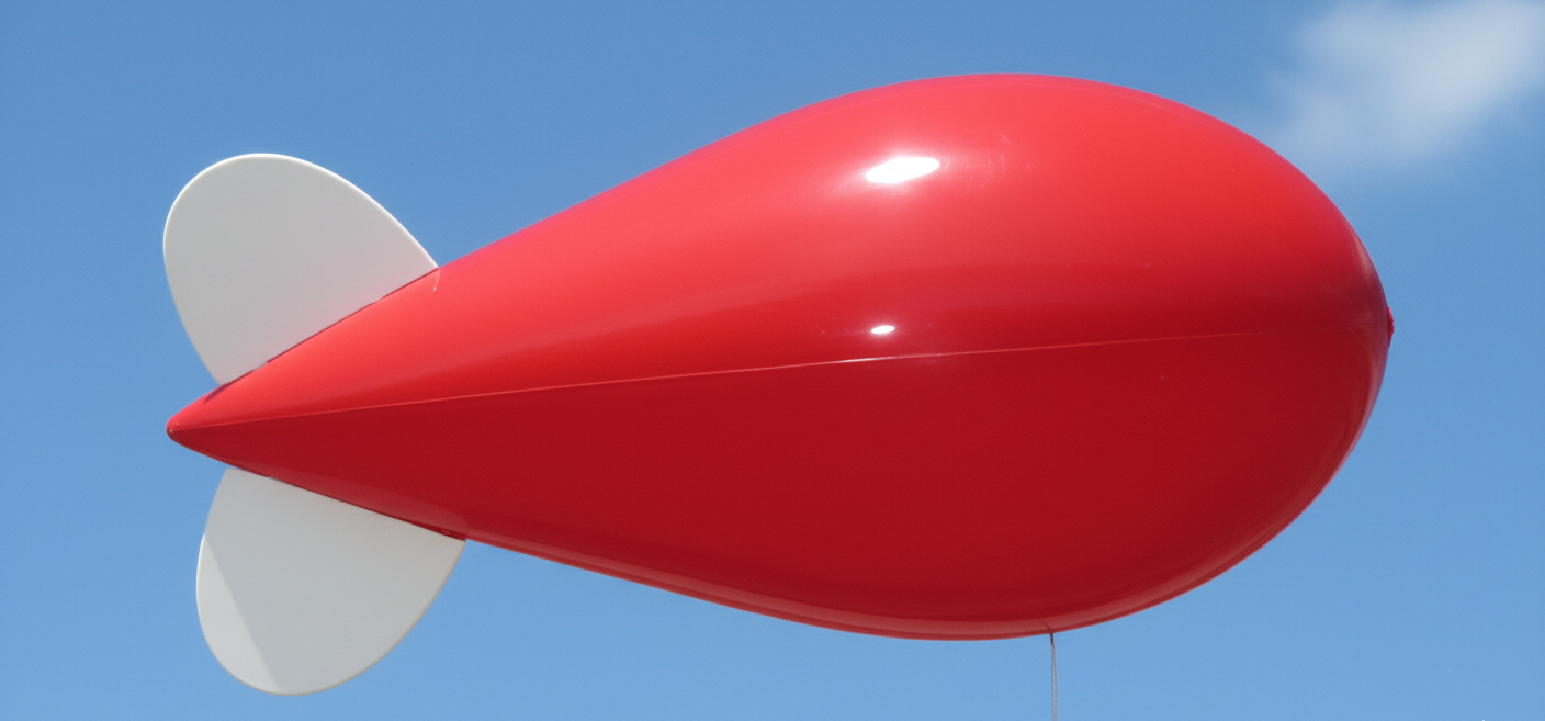 10ft bright red helium advertising blimp flying against a clear blue sky